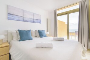 A hotel room with a large bed, a view of the sea, and a balcony.