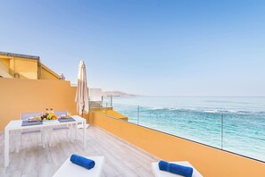 A balcony with a table set for breakfast, overlooking the sea.