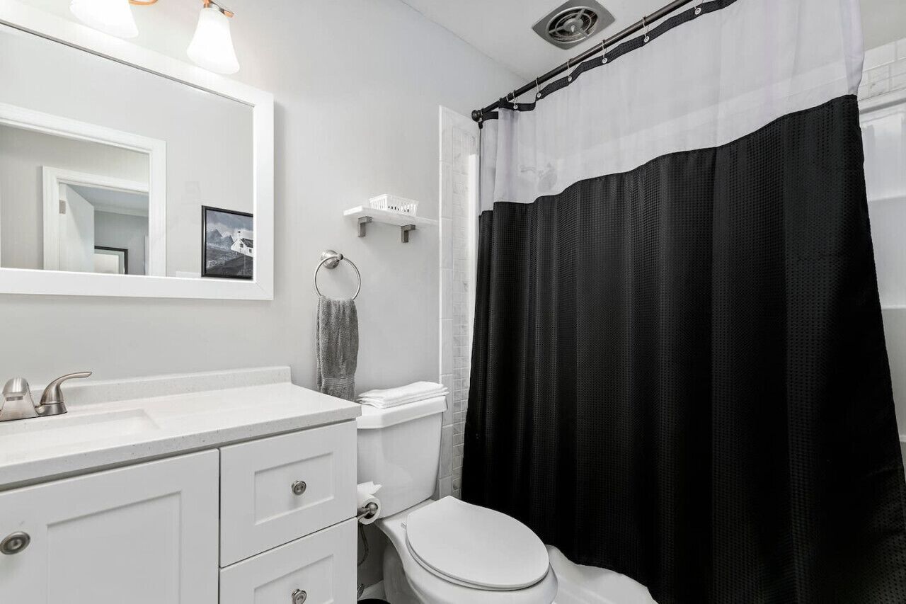 Un baño moderno con un lavamanos blanco, un inodoro y una cortina de ducha.