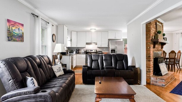 A modern living room with a black leather sofa, a wooden coffee table, and a fireplace. - Modern Charm & Garden View sleeps 6 (Greensboro)