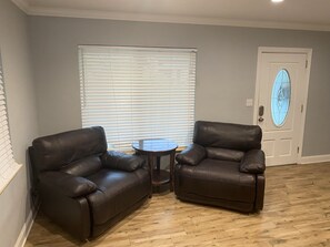 A living room with two leather sofas, a small round table, and a door with a stained glass window.