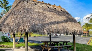 Una construcción con techo de paja y una mesa de picnic al frente.
