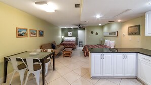 Una habitación de hotel compacta con kitchenette, comedor y cama.