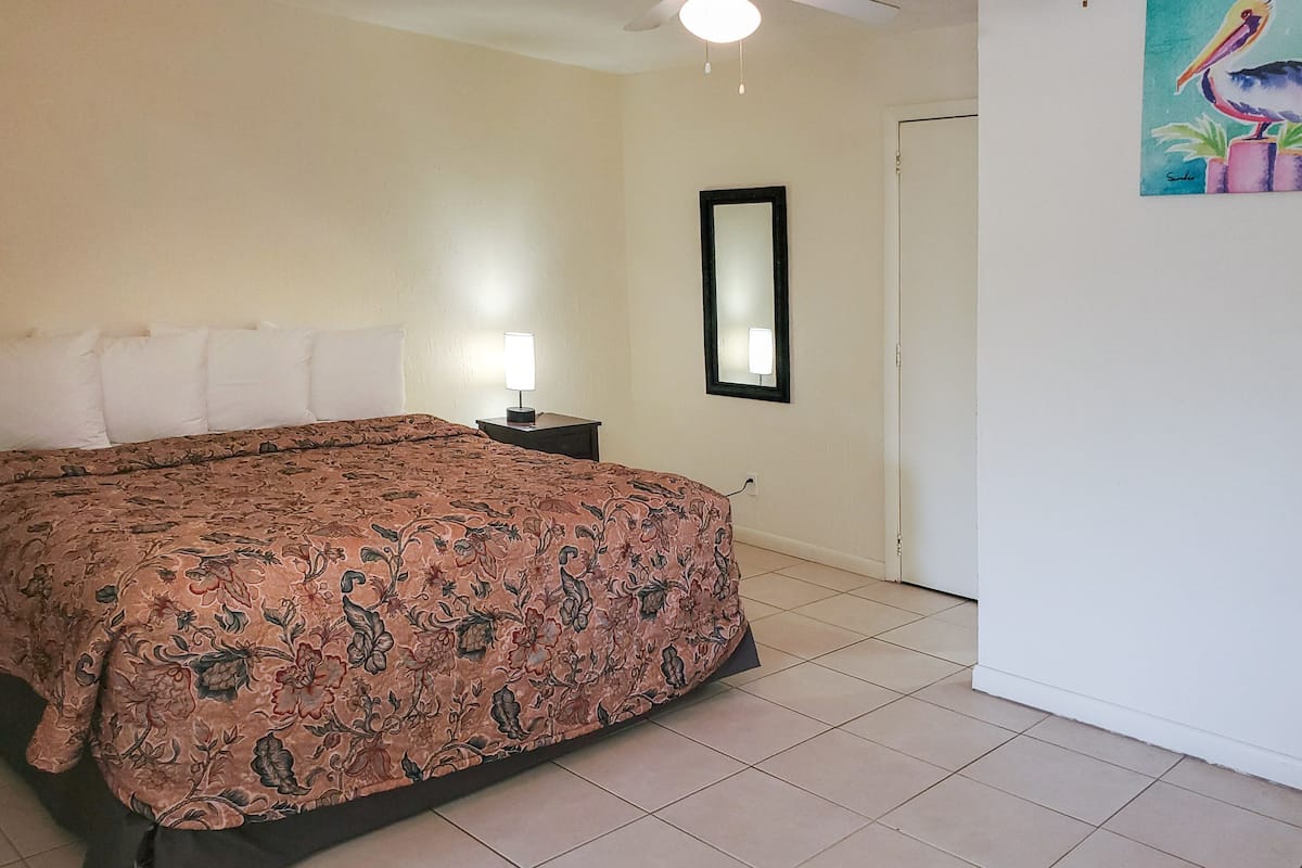 A bedroom with a bed, nightstands, a mirror, and a door.