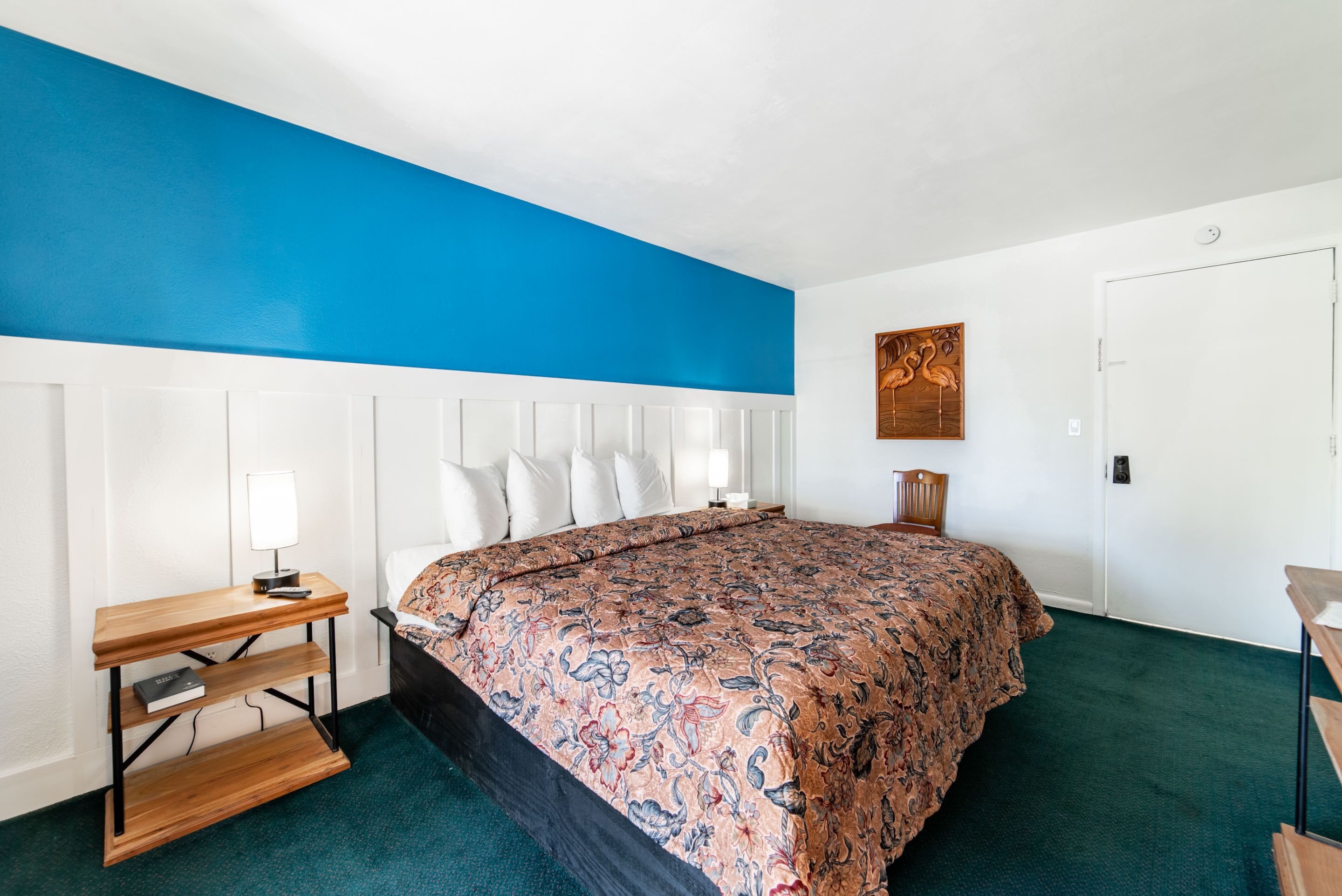 A bedroom with a large bed, a bedside table with a lamp, and a wooden headboard.