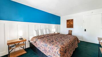 A bedroom with a large bed, a bedside table with a lamp, and a wooden headboard.