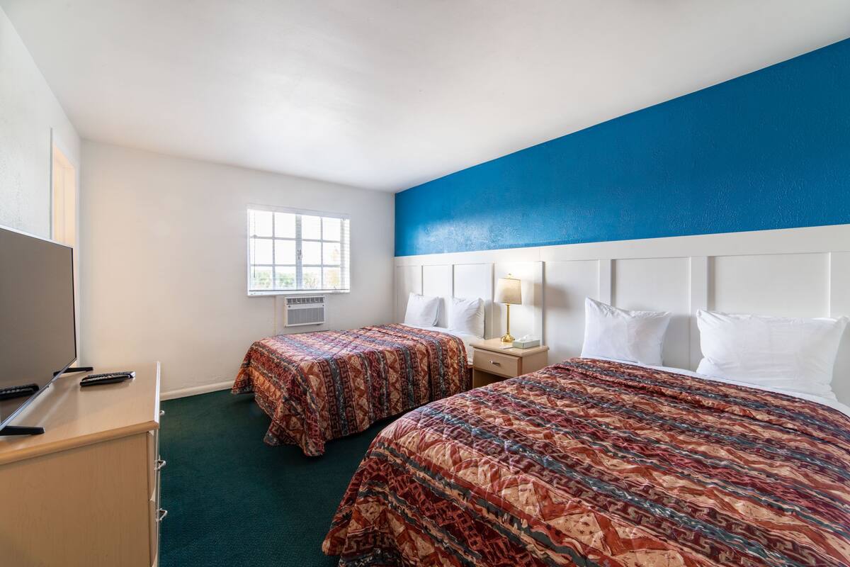 A hotel room with two beds, a TV, and a window.
