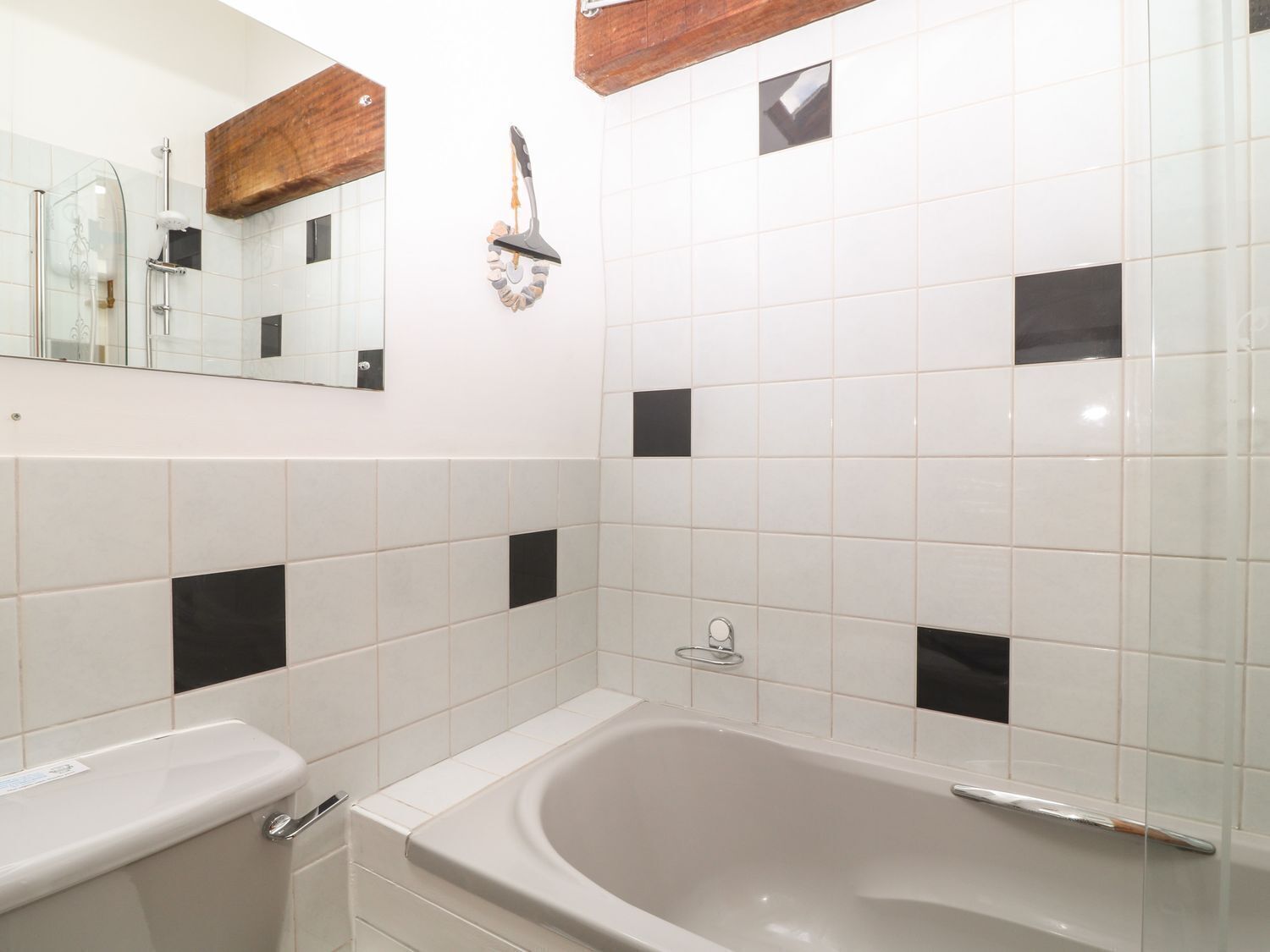 A bathroom with a bathtub, a toilet, and a mirror.