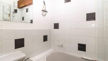Ein Badezimmer mit einer Badewanne, einer Toilette und einem Spiegel.