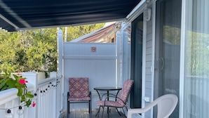 A covered deck with outdoor furniture, a white railing, and a no-smoking sign.