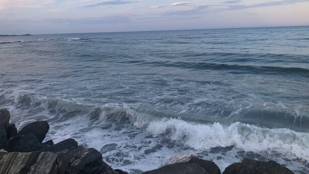 A coastal view with waves crashing against rocks.