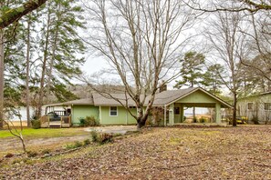 A single-story house with a porch, surrounded by trees and a yard with fallen leaves.