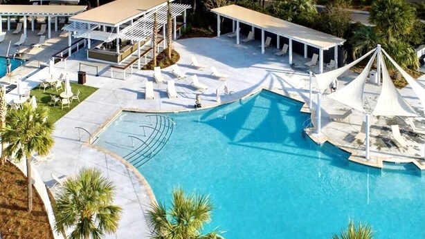 Uma grande piscina ao ar livre com espreguiçadeiras e palmeiras.