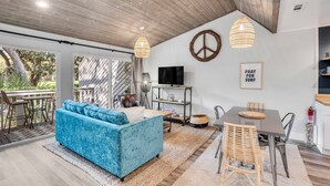 Uma sala moderna com um sofá azul, uma mesa de jantar e uma televisão.
