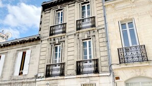 Un edificio de varios pisos con estilo arquitectónico clásico, con ventanas simétricas y elaboradas barandillas de hierro forjado.