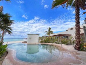A swimming pool with a view of the beach and palm trees.