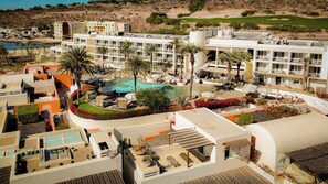 A resort with multiple buildings, a central pool, and surrounding greenery.