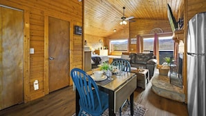 A wooden cabin interior with a dining area, a sofa, and a kitchen. - Great View, Location, Studio Log Cabin, Hot Tub! (Gatlinburg)