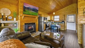 A cozy cabin interior with a fireplace, a dining area, and a kitchen. - Great View, Location, Studio Log Cabin, Hot Tub! (Gatlinburg)
