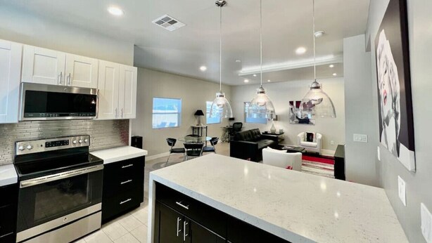 Una cocina moderna con electrodomésticos de acero inoxidable, gabinetes negros y una isla grande.