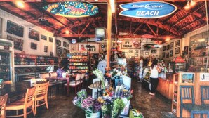 A cozy cafe with a rustic wooden ceiling, a Bud Light sign, and a variety of snacks and flowers on display. - RelaxBeachPad Beachside Studio!Parking&Laundry (San Pedro)