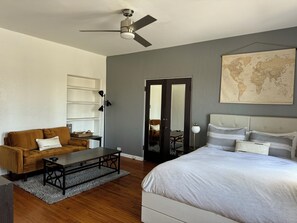 A bedroom with a bed, a sofa, a table, and a world map on the wall.