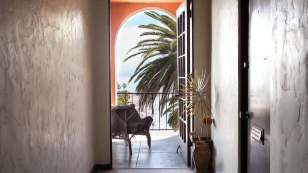 A hallway leading to a balcony with a view of palm trees and a building. - RelaxBeachPad Beachside Studio!Parking&Laundry (San Pedro)