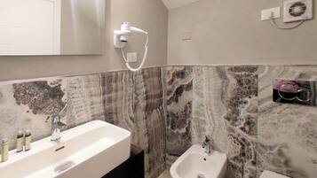 Een badkamer met een wastafel, een bidet en een aan de muur bevestigde haardroger.
