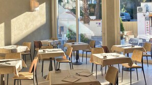 Un comedor con mesas y sillas, ventanas amplias y vistas al exterior.