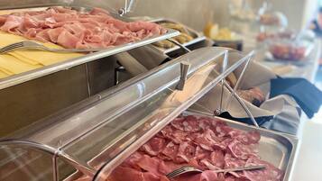 Buffet com diversos tipos de frios expostos em recipientes transparentes.