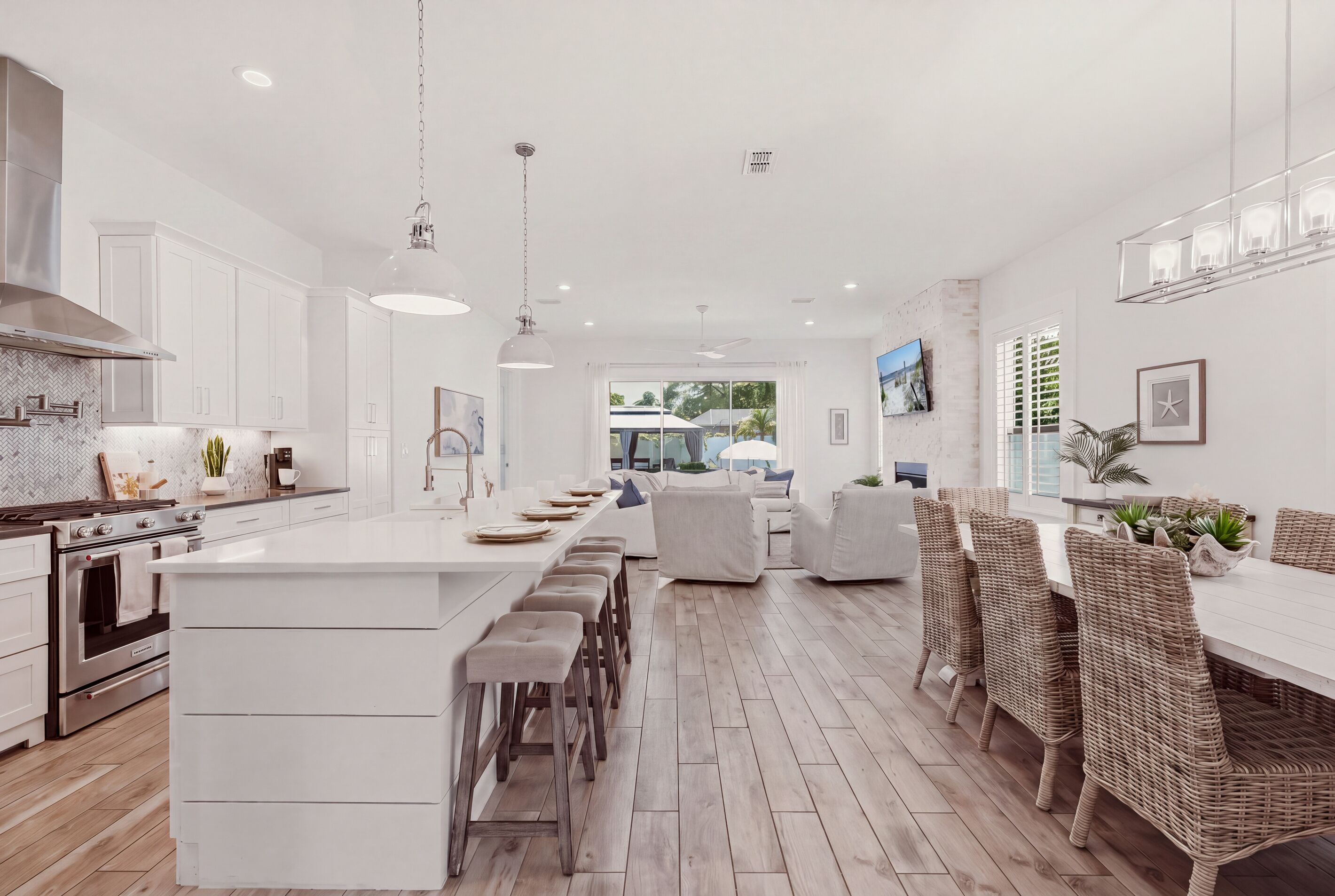 A modern kitchen with a central island, bar stools, and a dining area with wicker chairs.
