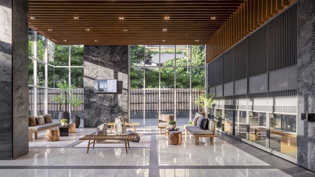 A spacious lobby with a high ceiling, hanging pendant lights, a central seating area, and large windows offering views of greenery. - Wyndham Garden Bangkok Sukhumvit 42 (Bangkok)