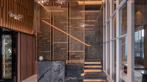 A modern interior with a staircase, wooden paneling, and a marble reception desk. - Wyndham Garden Bangkok Sukhumvit 42 (Bangkok)