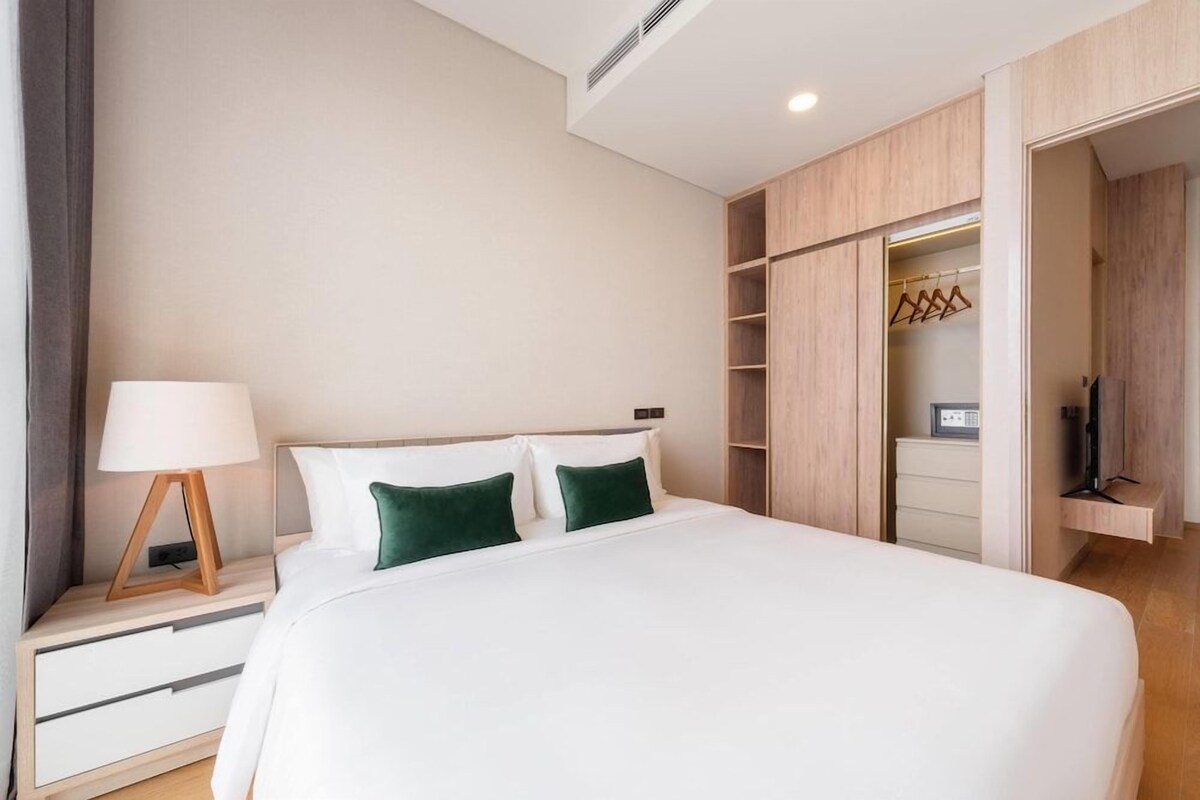 A hotel room with a bed, a nightstand, a lamp, a wardrobe, and a television.