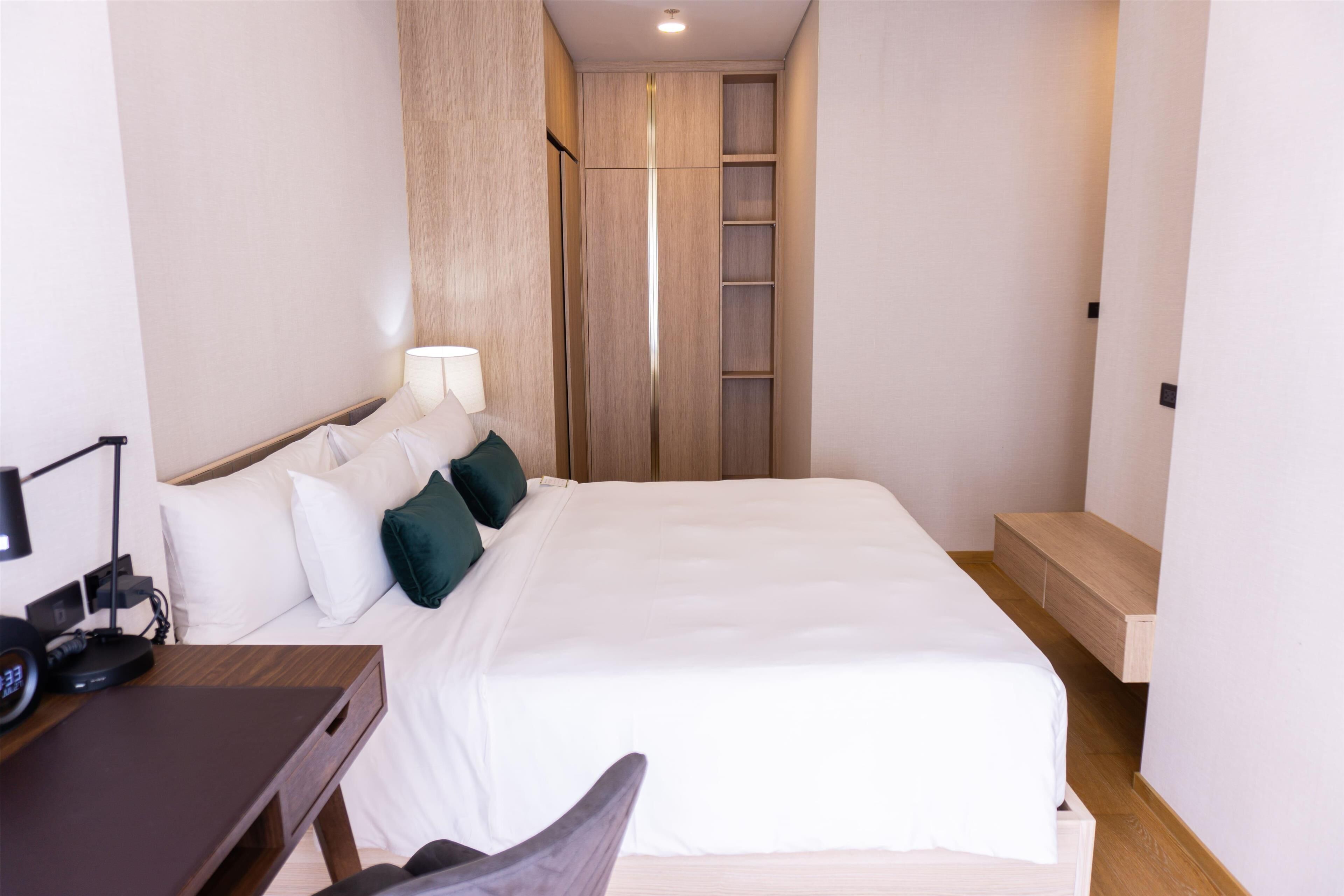 Ein Hotelzimmer mit einem großen Bett, einem Schreibtisch mit Lampe und einem Kleiderschrank mit Spiegel.