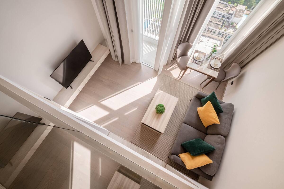 A modern living room with a sofa, coffee table, and TV, featuring a balcony view.