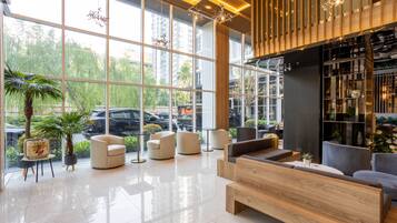 Un vestíbulo moderno con amplias ventanas, una recepción, zona de estar y una estantería.