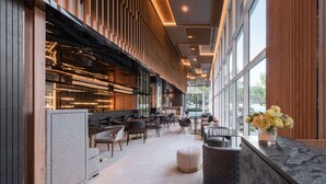 A modern interior with a long corridor lined with seating areas and a bar. - Wyndham Garden Bangkok Sukhumvit 42 (Bangkok)