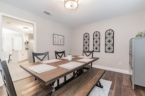 A dining room with a wooden table, chairs, and a bench. There are decorative wall pieces and a framed picture on the wall.