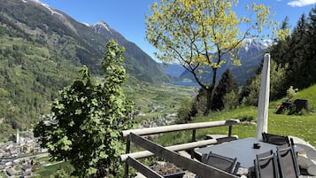 A scenic view of a mountainous area with a dining area featuring a table and chairs.