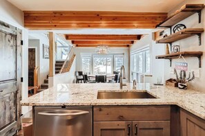 A kitchen with granite countertops, stainless steel appliances, wooden cabinets, and a hanging light fixture. - Ski/Golf Duplex-Views, Base of Mtn, Close to Lifts (Copper Mountain)