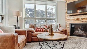 Una sala de estar acogedora con un amplio ventanal, chimenea y un sofá de cuero.