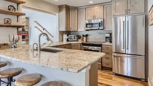 Una cocina moderna con encimeras de granito, electrodomésticos de acero inoxidable y armarios de madera.
