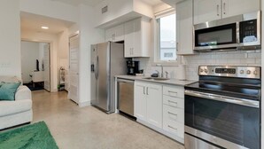 A modern kitchen with stainless steel appliances, white cabinetry, and a green rug. - Urban Oasis Spacious King Bed Free Parking (Nashville)