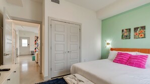 A bedroom with a bed, a dresser, a wardrobe, and a hallway leading to another room. - Urban Oasis Spacious King Bed Free Parking (Nashville)