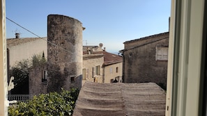 A narrow street with old buildings, a large stone tower, and a tiled roof.