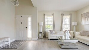 A modern living room with a white sofa, a coffee table, and a fireplace.
