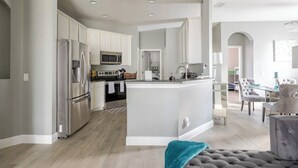 A modern kitchen with white cabinets, stainless steel appliances, and a central island.