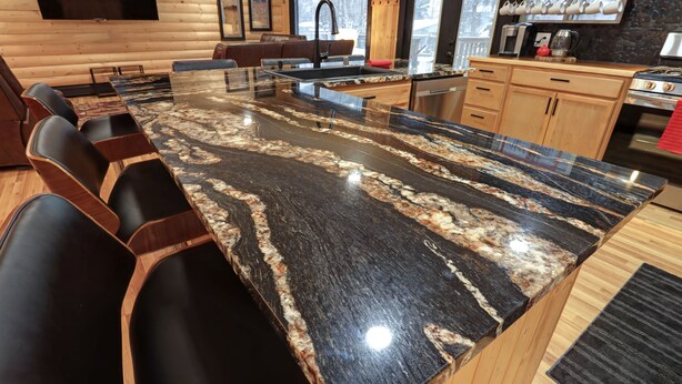 Una cocina con una encimera de granito, armarios de madera y horno empotrado.