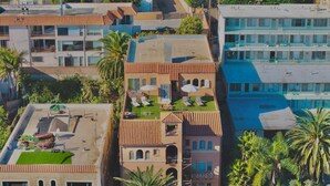 A hotel with multiple buildings, including a rooftop pool area with sun loungers and umbrellas, surrounded by palm trees. - Mid Century Modern Beachside. Laundry. Parking (San Pedro)